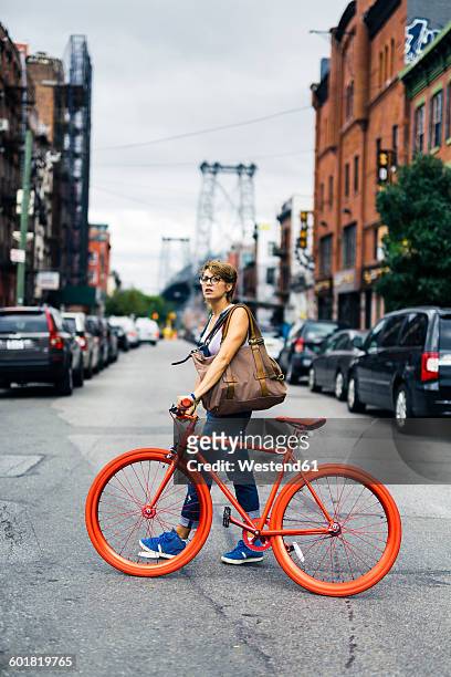 usa, new york city, williamsburg, woman withg red racing cycle crossing the street - williamsburg brooklyn stockfoto's en -beelden