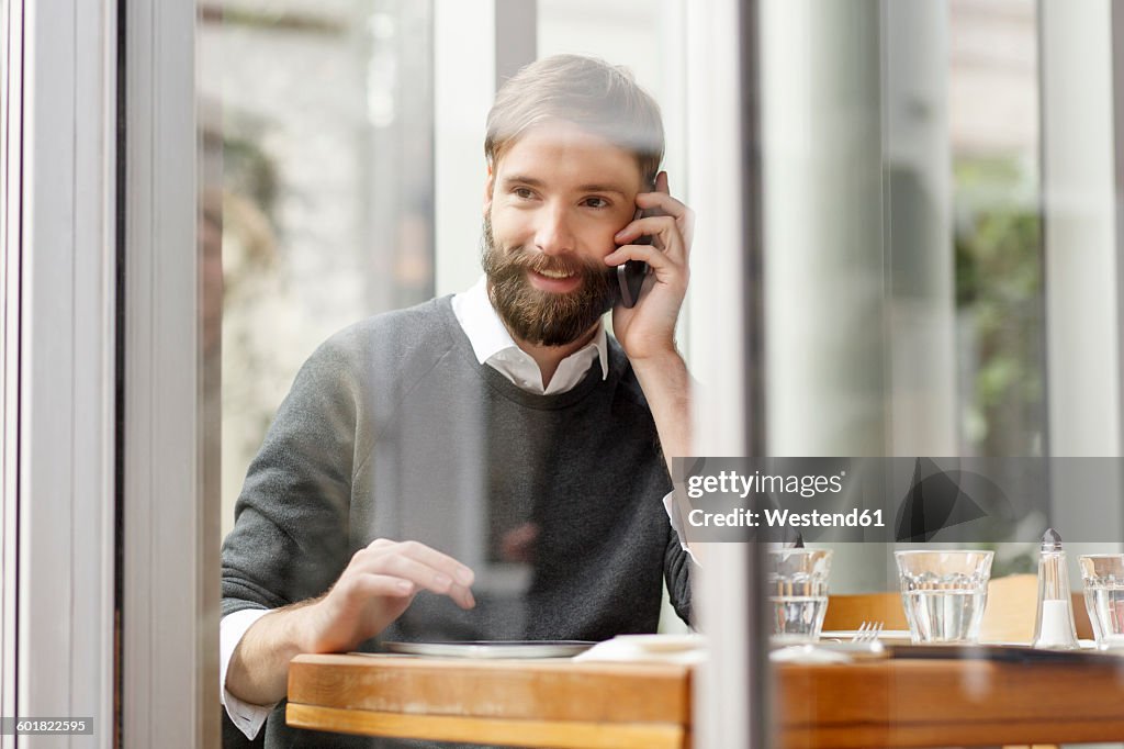 Smiling young man on cell phone in restaurant