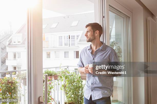 serious man looking out of window - balcony view stock-fotos und bilder