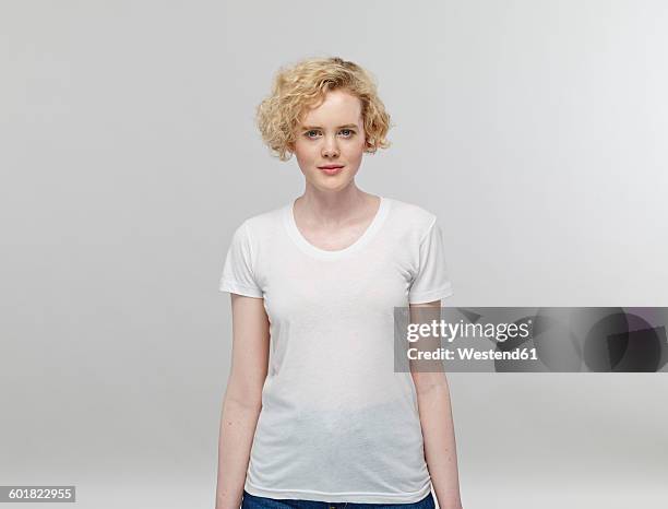 portrait of blond woman wearing white t-shirt in front of grey background - caucasian ethnicity stock-fotos und bilder