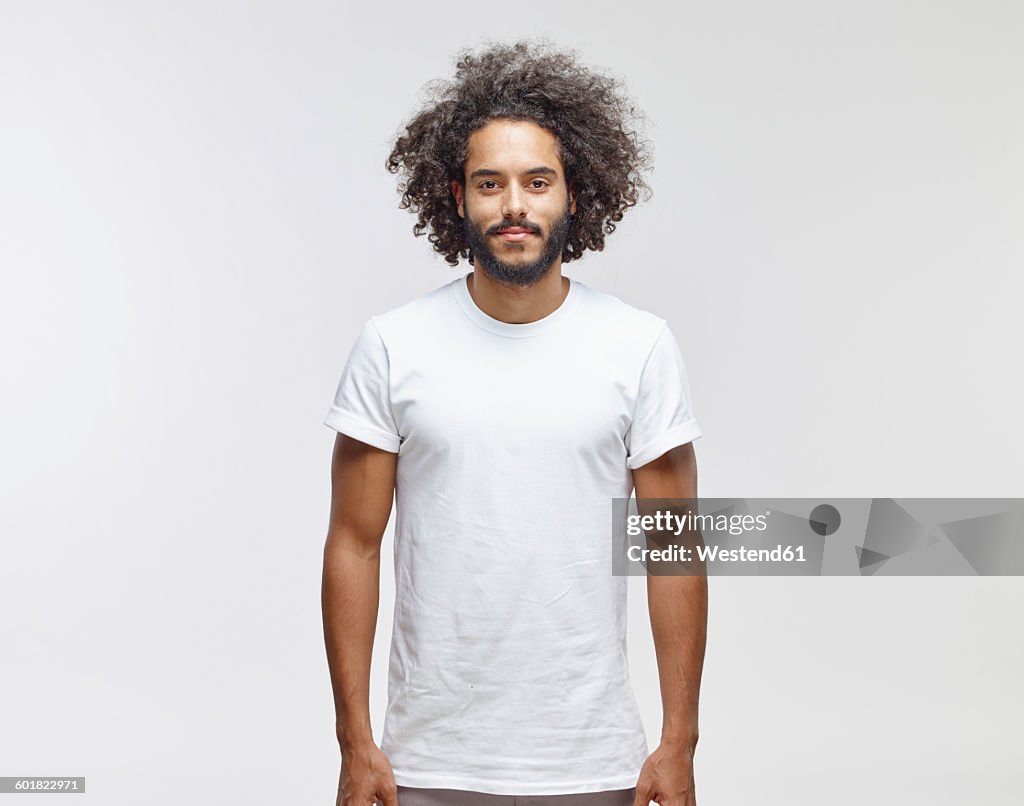 Portrait of bearded young man with curly brown hair wearing white t-shirt