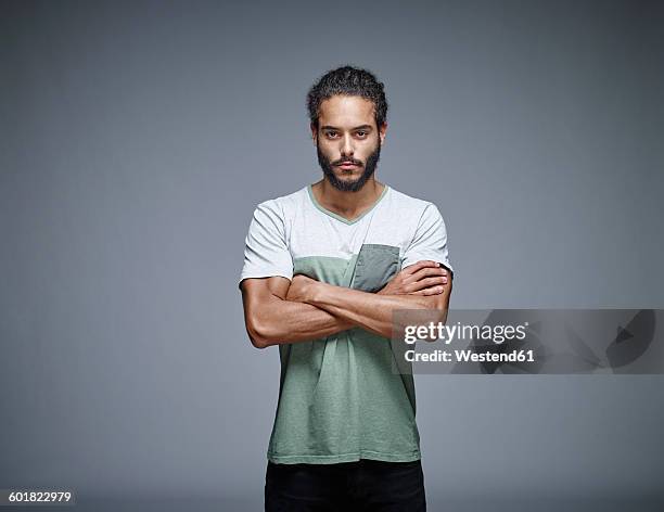 portrait of bearded young man with crossed arms in front of grey background - man standing and gesturing stock pictures, royalty-free photos & images