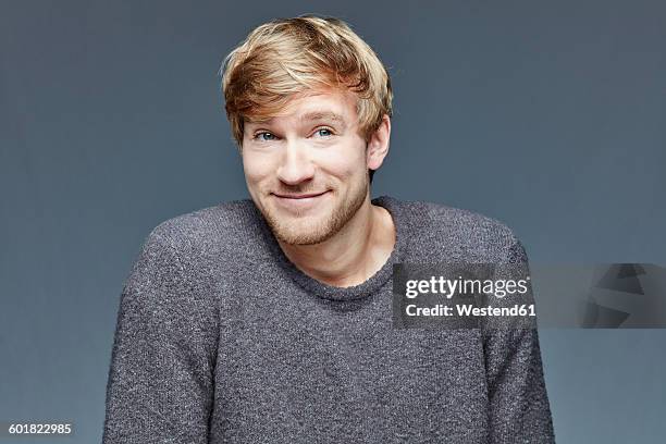 portrait of smiling blond man in front of grey background - bad bangs imagens e fotografias de stock