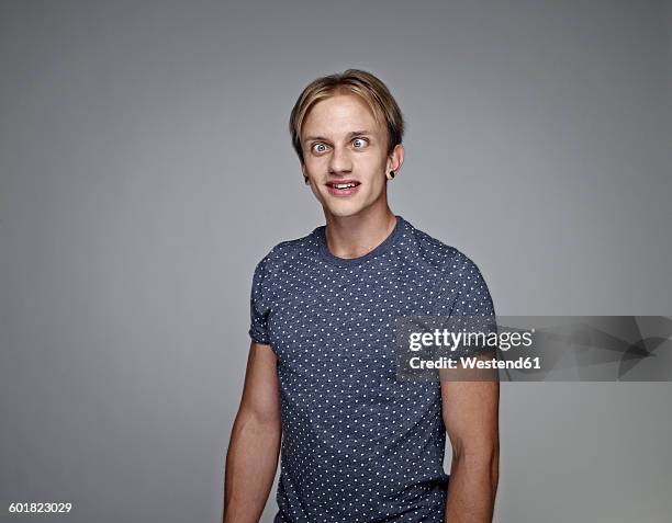 portrait of cross-eyed young man in front of grey background - louche photos et images de collection