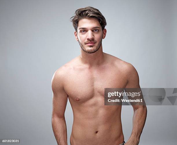portrait of shirtless young man in front of grey background - sin camisa fotografías e imágenes de stock