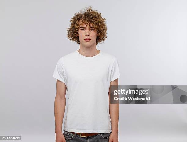 portrait of young man with curly blond hair wearing white t-shirt - t-shirt stock-fotos und bilder