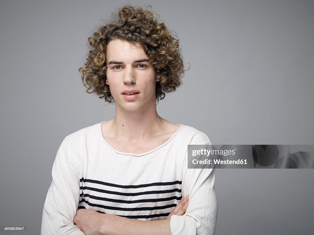 Portrait of young man with curly blond hair and arms crossed