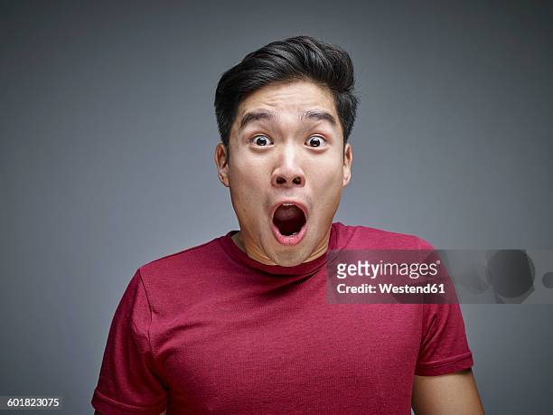 portrait of shocked young man in front of grey background - disbelief stock pictures, royalty-free photos & images