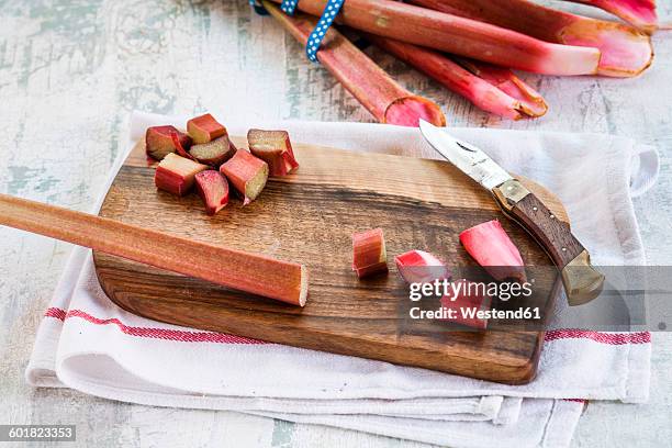 rhubarb stalks, cut in pieces, board and knife - rabarber stockfoto's en -beelden