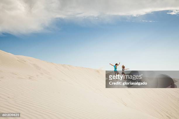 boy and girl jumping in sand dunes, green head, western australia, australia - jumping australia stock-fotos und bilder