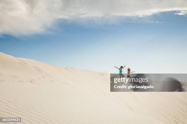 boy and girl jumping in sand dunes, green head, western australia, australia - blue sky friends stock pictures, royalty-free photos & images