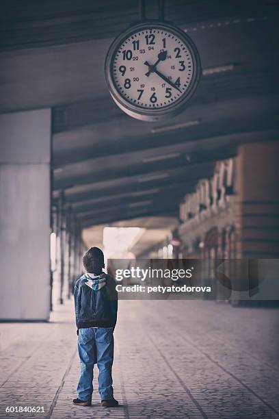 boy looking up at clock - tijdmeter stockfoto's en -beelden