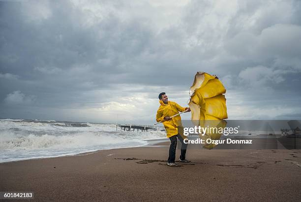 man on windy beach - broken umbrella stockfoto's en -beelden