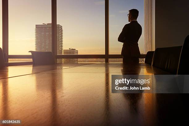 businessman in boardroom at dusk. - executive office chair stock pictures, royalty-free photos & images