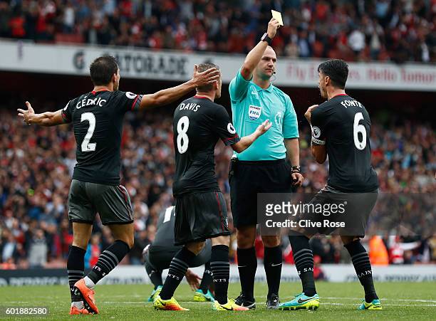 Bobby Madley gives Jose Fonte of Southampton a yellow card for a foul in the box during the Premier League match between Arsenal and Southampton at...