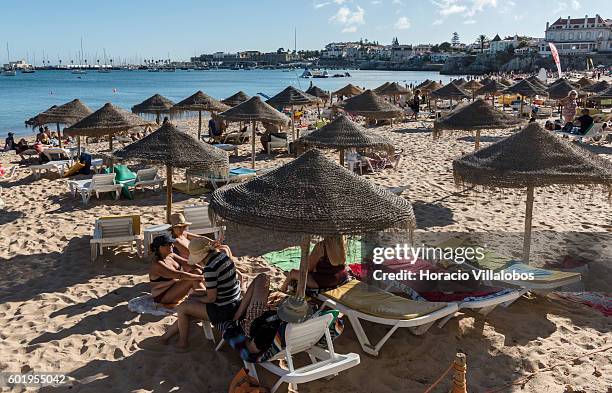 Beachgoers and sun umbrellas in Praia da Duquesa on September 09, 2016 in Cascais, Portugal. Although active all year round, Portuguese tourist...