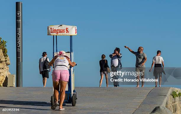 Vendor pushes her food cart while visitors stroll by Praia da Duquesa on September 09, 2016 in Cascais, Portugal. Although active all year round,...