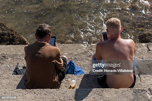 Beachgoers use a Kindle and Smart Phone while sunbathing in Praia da Duquesa on September 09, 2016 in Cascais, Portugal. Although active all year...