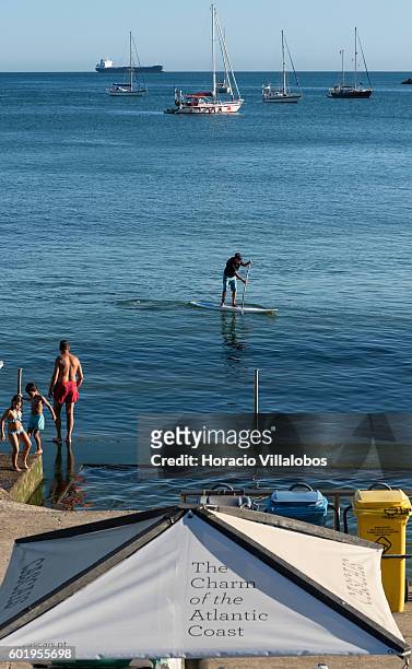 Beachgoers and spade surfer in Praia da Duquesa on September 09, 2016 in Cascais, Portugal. Although active all year round, Portuguese tourist...