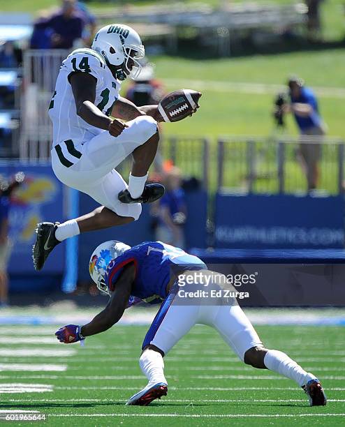 Quarterback Greg Windham of the Ohio Bobcats leaps over cornerback Marnez Ogletree of the Kansas Jayhawks as he picks up a first down in the first...