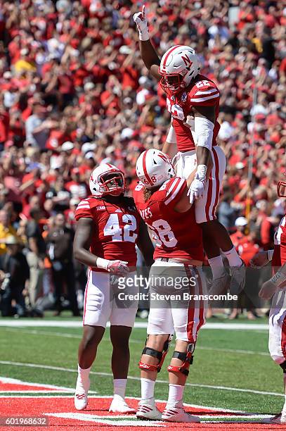Running back Devine Ozigbo gets lifted by offensive lineman Nick Gates as tight end Trey Foster of the Nebraska Cornhuskers looks on after scoring...