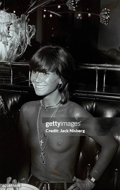 Jennifer Chambon wearing a sheer top by Courreges, suede pants by New Man; she wears a cross by Capri, choker, chains with medallions by Van Cleef.