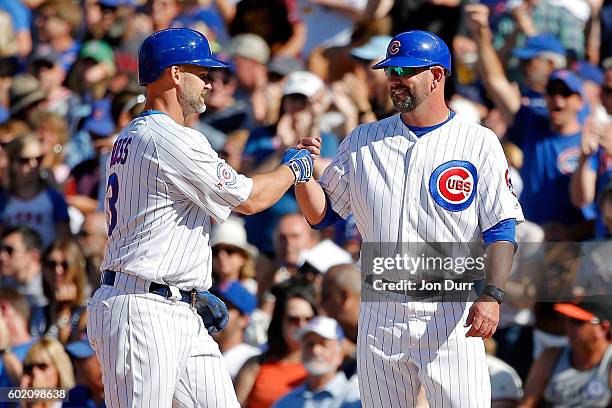 First base coach Brandon Hyde of the Chicago Cubs congratulates David Ross after he hit a single against the San Francisco Giants during the ninth...