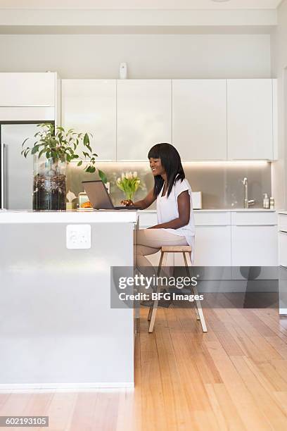 young woman using laptop in kitchen, cape town, south africa - sgabello foto e immagini stock