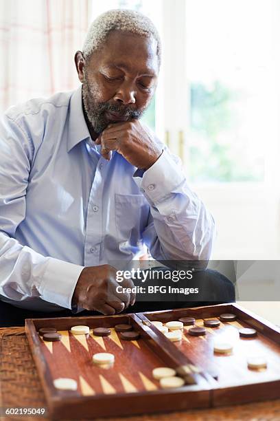 senior man playing backgammon, cape town, south africa - backgammon stock pictures, royalty-free photos & images