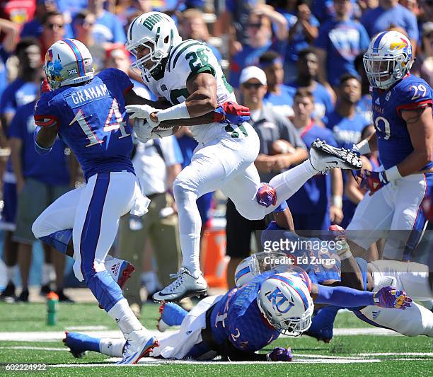 Dorian Brown of the Ohio Bobcats picks up yards against Chevy Graham, Bazie Bates IV and Brandon Stewart of the Kansas Jayhawks in the first quarter...