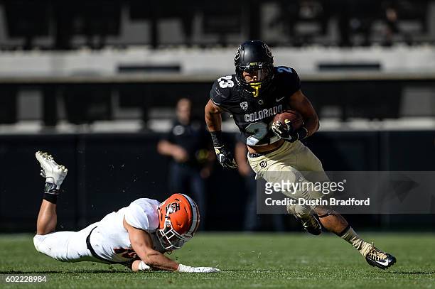 Running back Phillip Lindsay of the Colorado Buffaloes rushes and breaks a tackle by defensive back Taison Manu of the Idaho State Bengals in the...