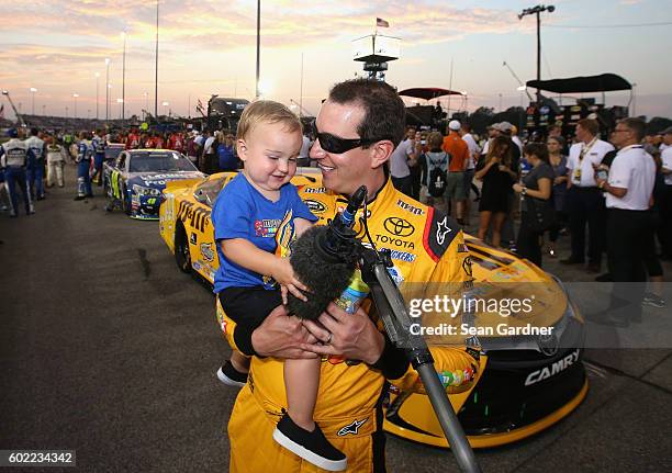 Kyle Busch, driver of the M&M's 75th Anniversary Toyota, reacts as his son Brexton plays with a TV microphone prior to the NASCAR Sprint Cup Series...