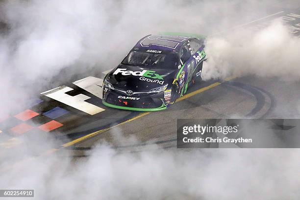 Denny Hamlin, driver of the FedEx Ground Toyota, celebrates with a burnout after winning the NASCAR Sprint Cup Series Federated Auto Parts 400 at...