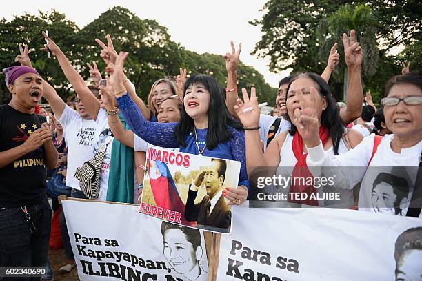 Supporters of the late Philippine dictator Ferdinand Marcos hold placards with slogans saying "for peace, should be buried" after releasing ballons...