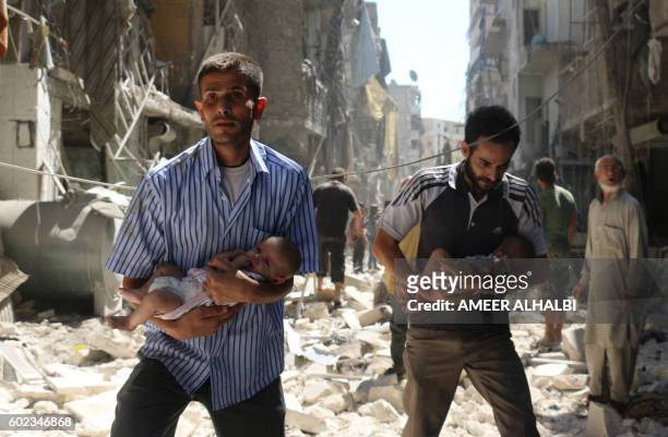 Syrian men carrying babies make their way through the rubble of destroyed buildings following a reported air strike on the rebel-held Salihin...