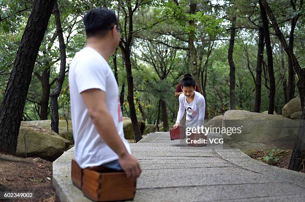 Legless motivational speaker Chen Zhou and legless teenager Gao Zhiyu climb the Mount Lao on September 10, 2016 in Qingdao, Shandong Province of...