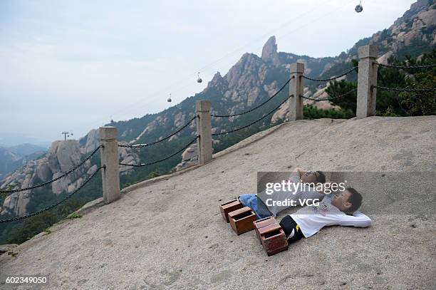 Legless motivational speaker Chen Zhou and legless teenager Gao Zhiyu lie on the Mount Lao on September 10, 2016 in Qingdao, Shandong Province of...