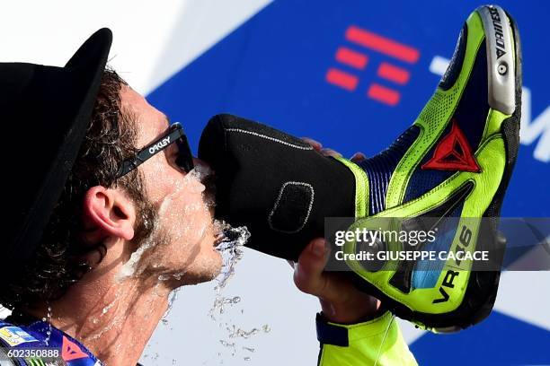 Movistar Yamaha MotoGP's Italian rider Valentino Rossi drinks from a shoe as he celebrates his second place on the podium of the San Marino Moto GP...