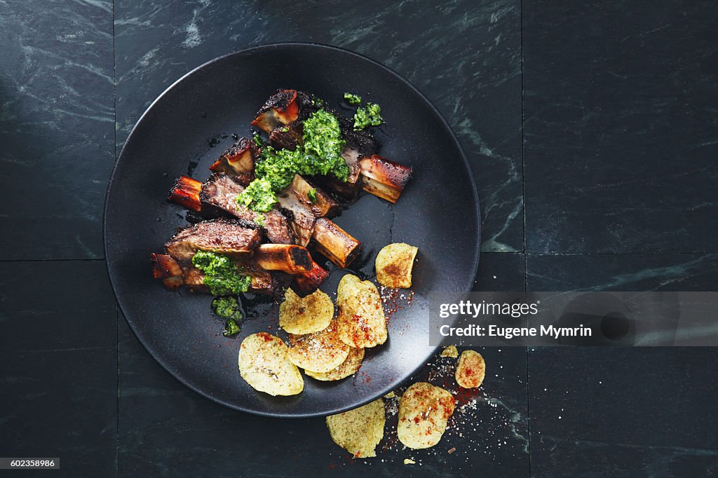 Grilled beef ribs with potato chips and parsley sauce