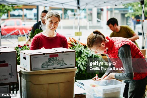 Farm owner setting up market stand with employee