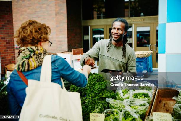 farmer taking credit card from customer - shopping bag stock photos et images de collection