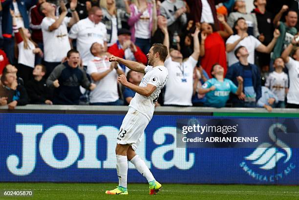 Swansea City's Icelandic midfielder Gylfi Sigurdsson celebrates in front of their supporters after scoring their first goal from the penalty spot...