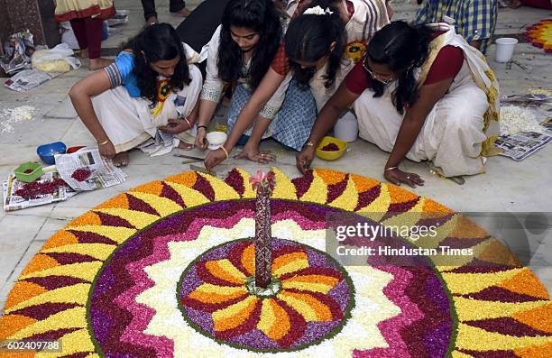 Malayali community members decorate a giant Pookalam, a rangoli made by using flowers of several colours, to welcome Bhagwan Mahabali to mark the...