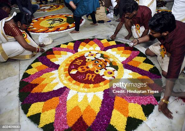 Malayali community members decorate a giant Pookalam, a rangoli made by using flowers of several colours, to welcome Bhagwan Mahabali to mark the...