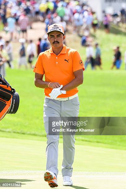 Rickie Fowler puts on his glove as he walks to the 17th hole green with caddie Joe Skovron during the final round of the BMW Championship at Crooked...