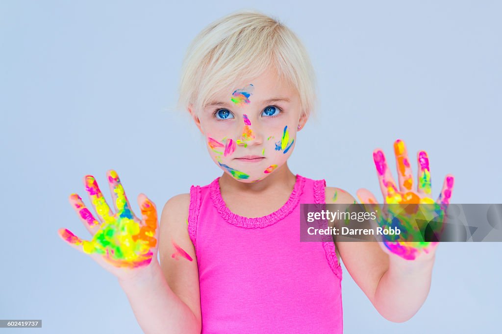 Girl with multi coloured paint on hands and face