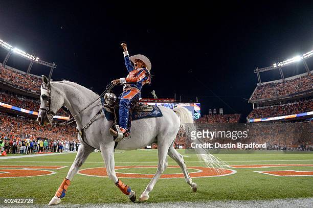 Ann Judge Wegener rides Denver Broncos mascot "Thunder" after a Denver Broncos score during a game between the Denver Broncos and the Carolina...
