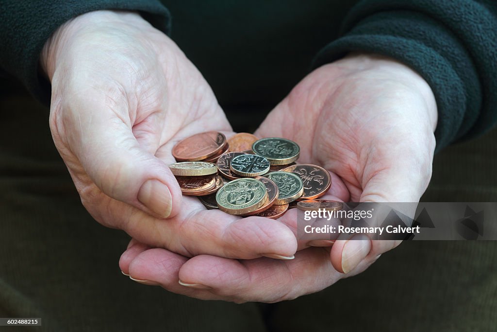 Hands holding small change in British coins
