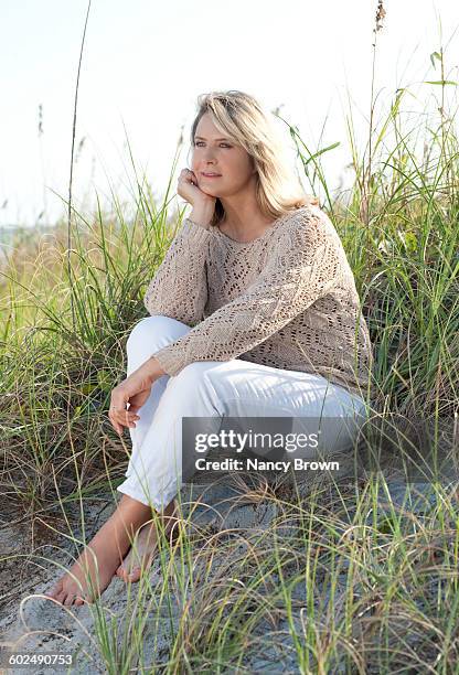 mature (55+) woman sitting in dunes - 頬杖点のイラスト素材／クリップアート素材／マンガ素材／アイコン素材