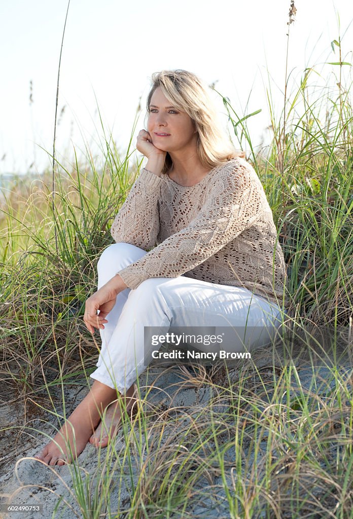 Mature (55+) woman sitting in dunes
